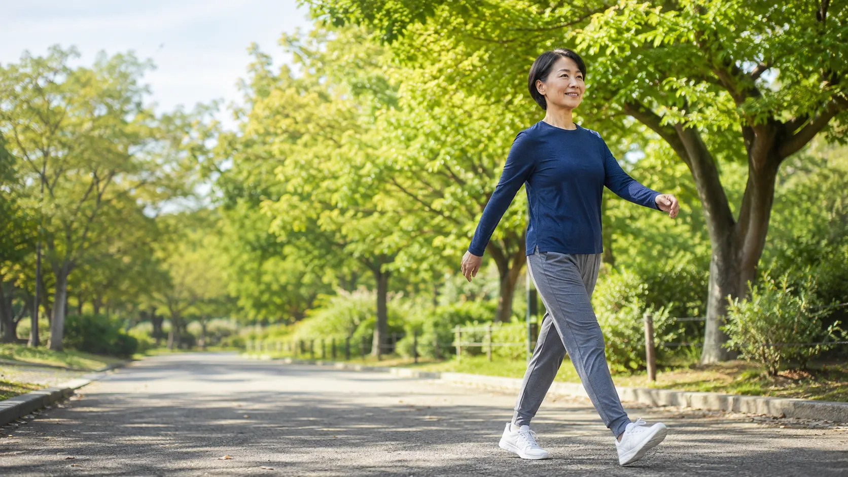 公園の道を歩く人物 ── 行動変容アプリ「運動サプリ®」のイメージ