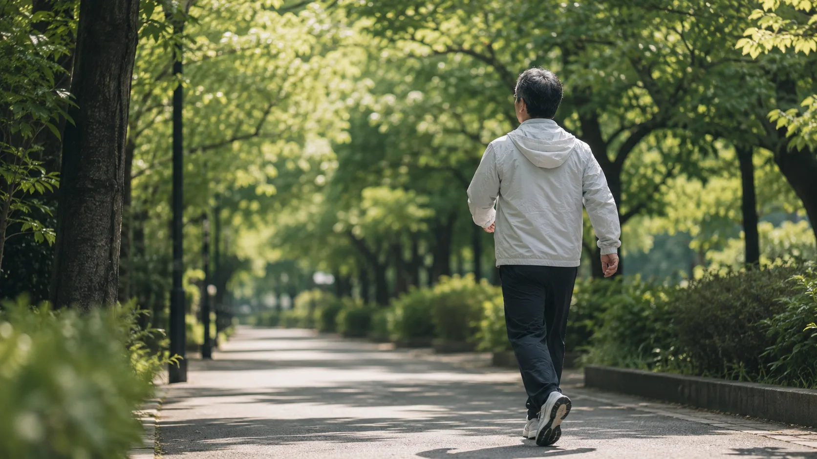 新緑の街路樹の下を、ひとり静かに歩いていく後ろ姿 ── ウォーキングに挑むチャレンジャーの象徴